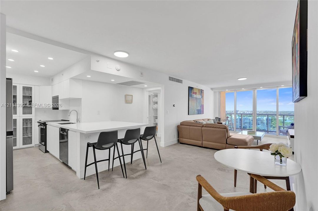 Living area featuring tile flooring, recessed ceiling lighting, and floor-to-ceiling glass sliding doors opening to a balcony with metal railings