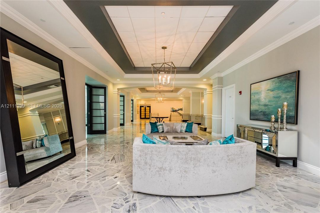 Expansive foyer featuring polished stone flooring with a mosaic pattern, coffered ceilings, crown molding, and metal lantern-style chandeliers