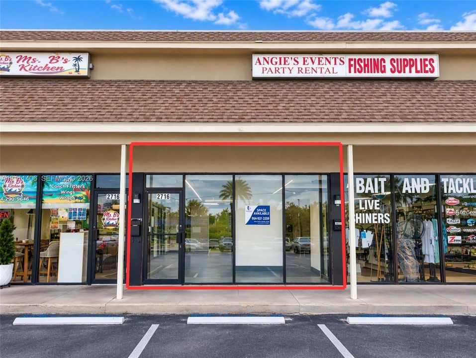 Commercial storefront featuring a glass-paneled entry door, expansive floor-to-ceiling windows, and dedicated parking space
