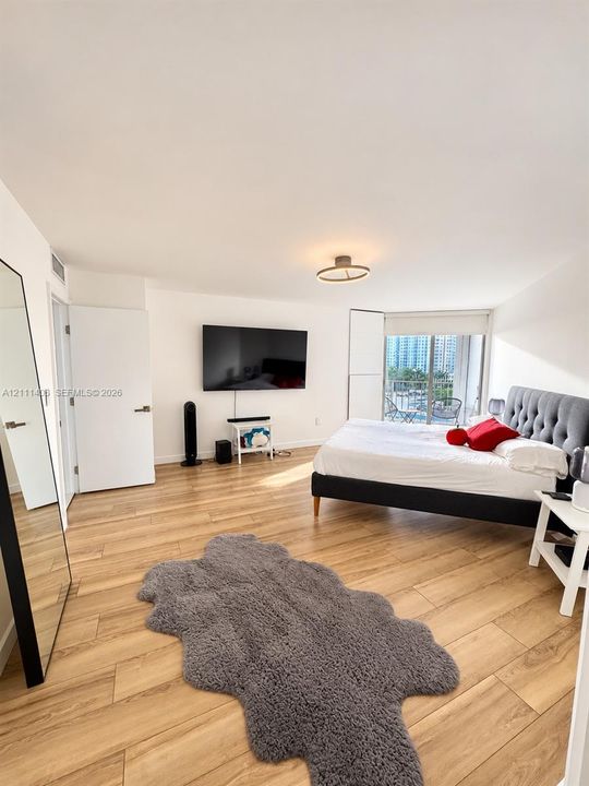 Wood-finish flooring, flush-mount circular lighting, and sliding glass doors leading to a balcony