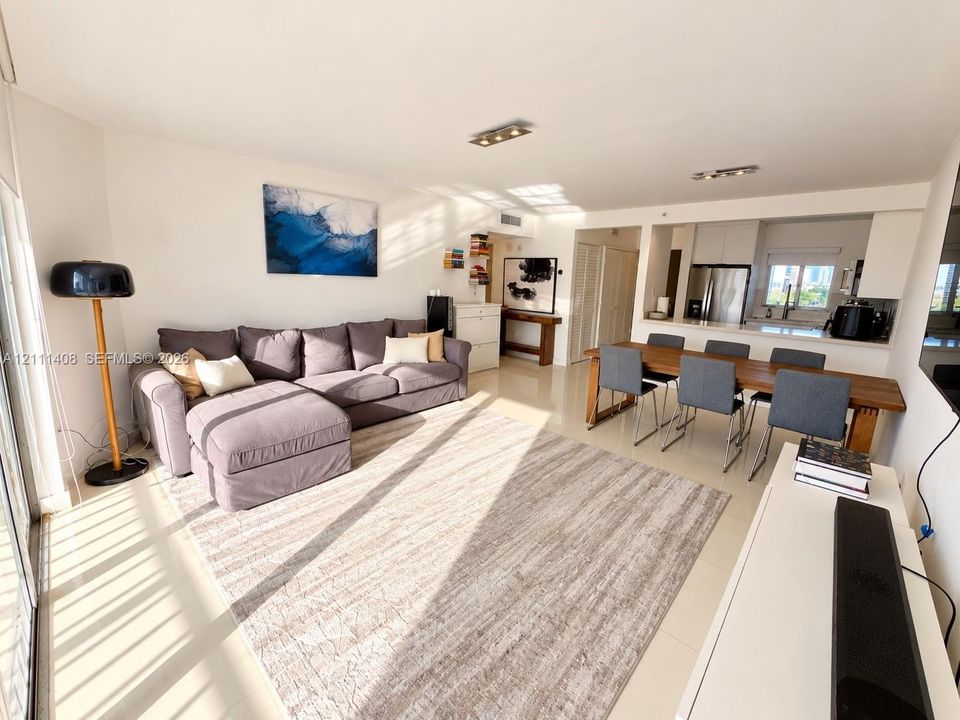 Open-concept floor plan featuring neutral tile flooring, recessed track lighting, and a kitchen equipped with stainless steel appliances