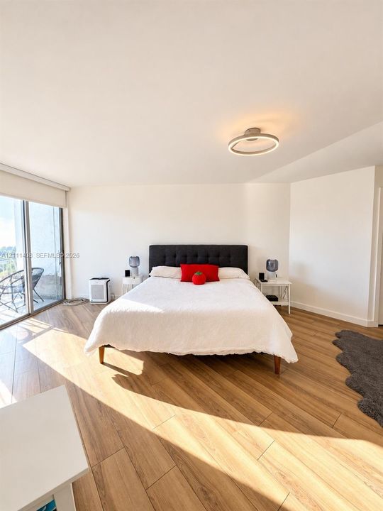 Wood-finish flooring, floor-to-ceiling sliding glass doors, and a modern circular LED ceiling fixture