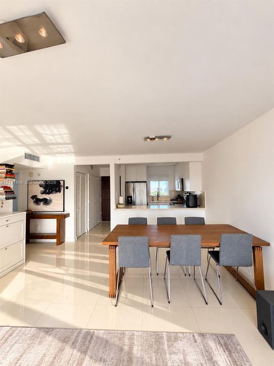 Open-concept interior featuring polished tile flooring, white cabinetry, stainless steel appliances, and flush-mount ceiling lighting