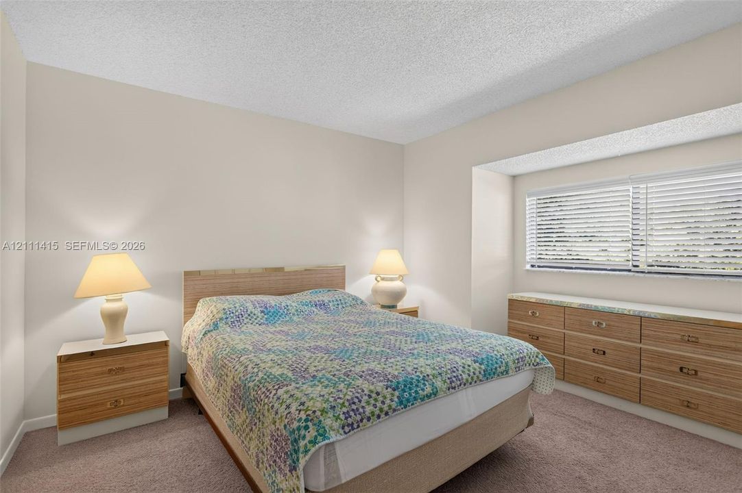 Bedroom featuring neutral wall paint, carpeted flooring, a recessed window nook, and built-in wood-finish cabinetry