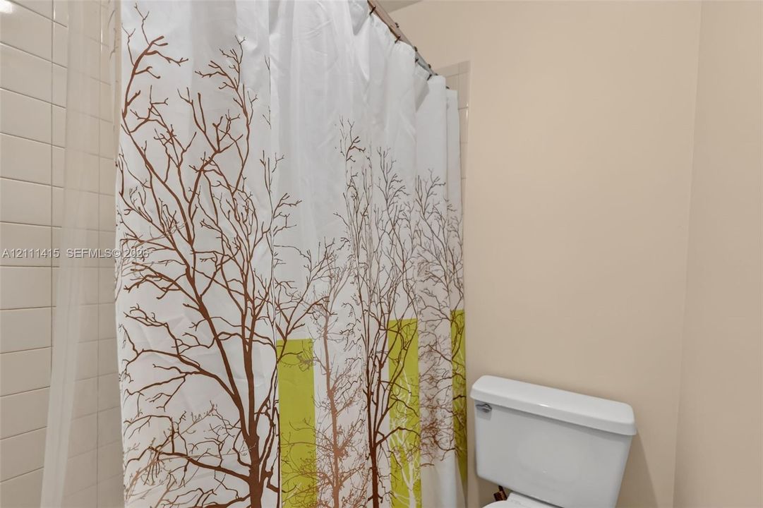Full-height ceramic wall tiling surrounding the shower and a standard-height porcelain toilet