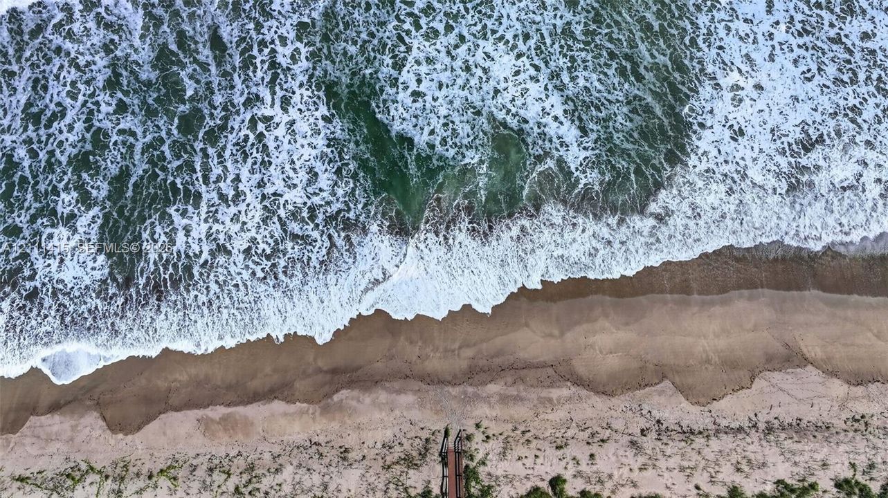 Direct oceanfront property featuring sandy beach access and a private stairway