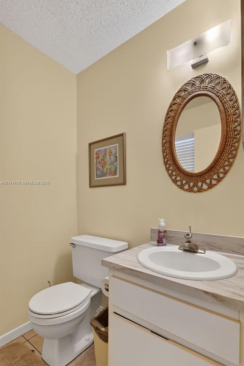 Vanity cabinet with a neutral-toned countertop, undermount sink, chrome faucet fixture, and wall-mounted frosted glass lighting