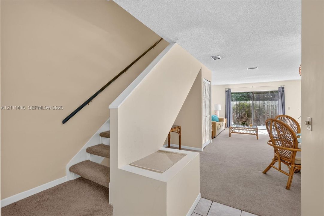 Staircase featuring carpeted steps and a metal handrail, finished with neutral wall paint and a sliding glass door