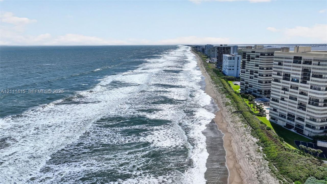 Direct oceanfront positioning featuring a sandy beach, expansive coastline, and multi-story structural architecture