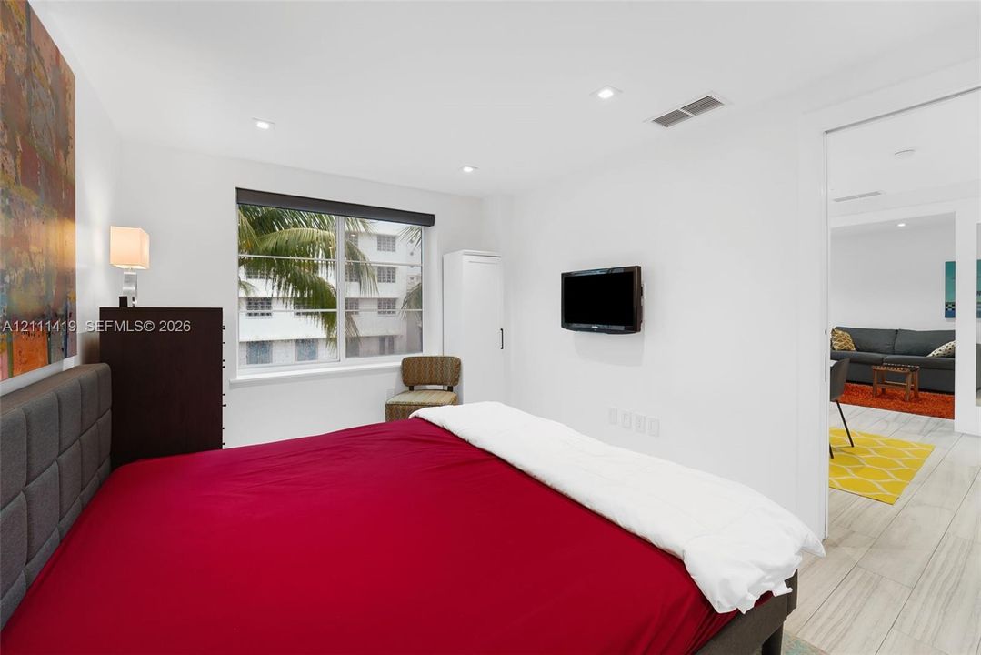 Neutral wall finishes, recessed lighting, and large horizontal window with exterior tropical foliage