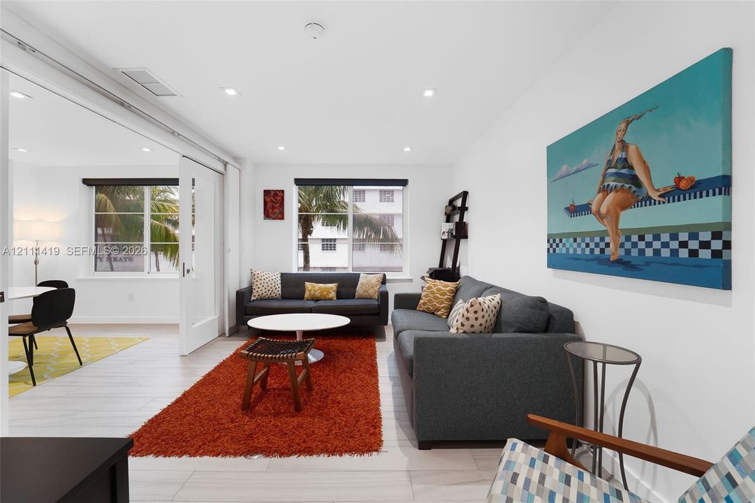 Interior space featuring light-toned tile flooring, recessed ceiling lighting, and a white sliding glass-paneled door