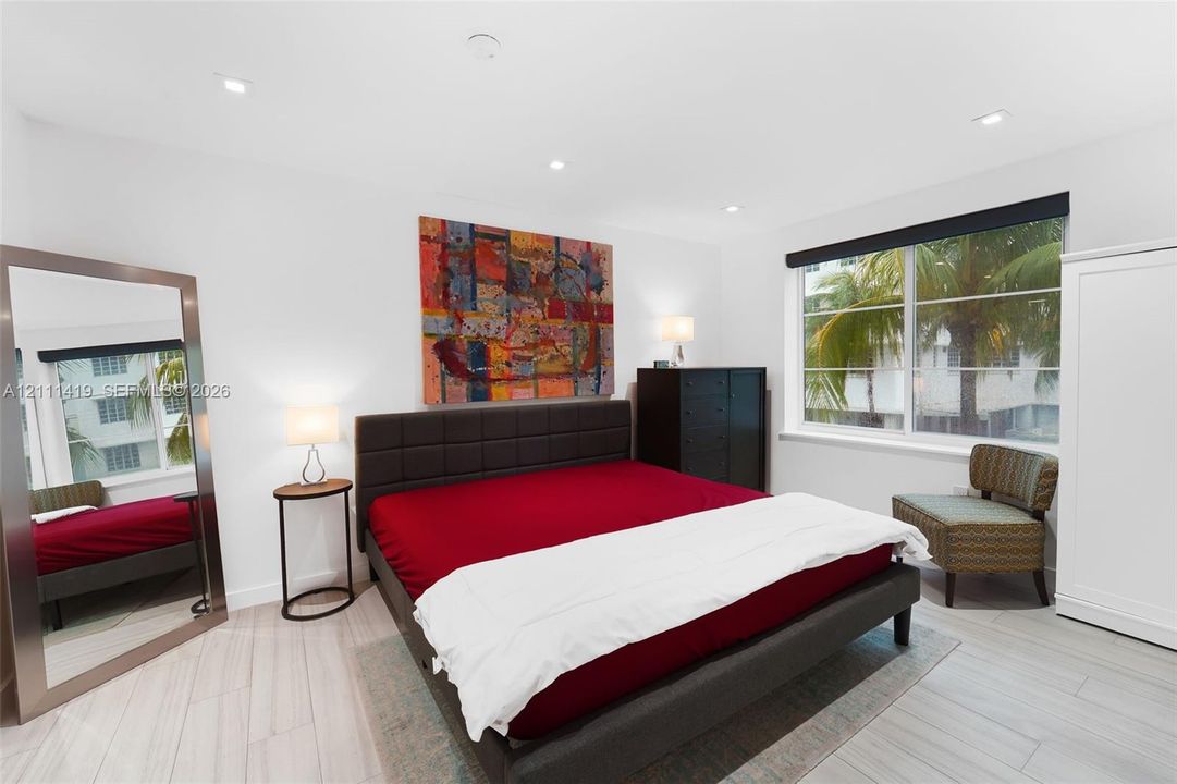 Neutral-toned space featuring large-format ceramic tile flooring, crisp white wall finishes, recessed ceiling lighting, and a wide window with dark trim