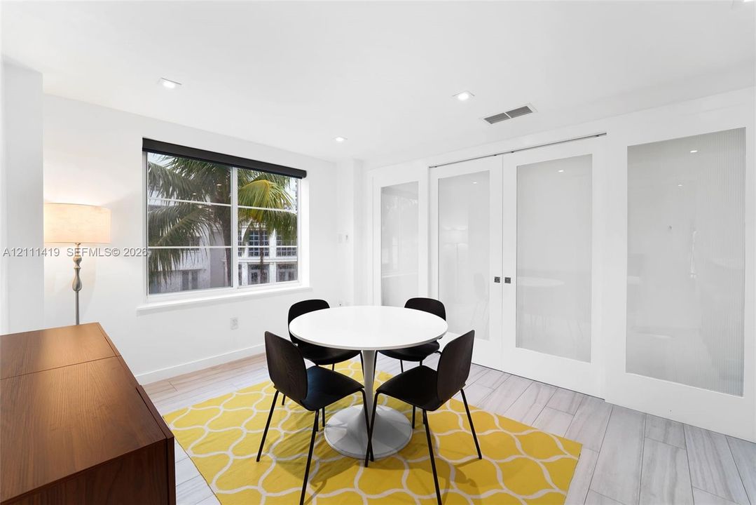 Light-filled room featuring wood-finish tile flooring, recessed ceiling lighting, and double French doors with frosted glass panels
