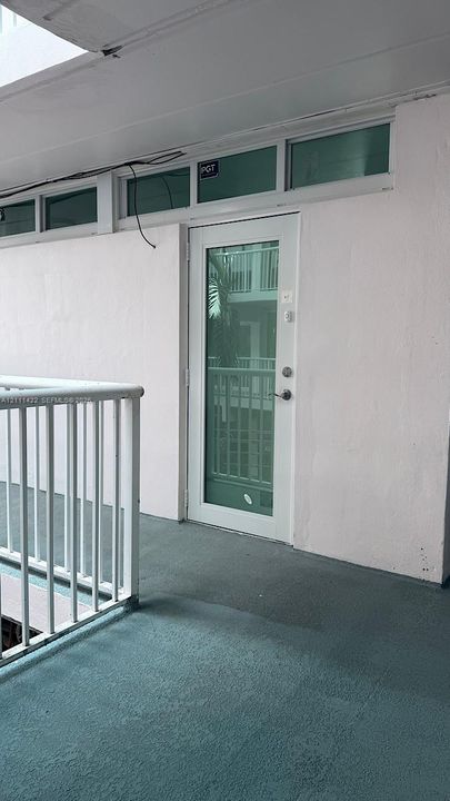Entryway featuring a glass-panel door, rectangular transom windows, and a white powder-coated metal railing