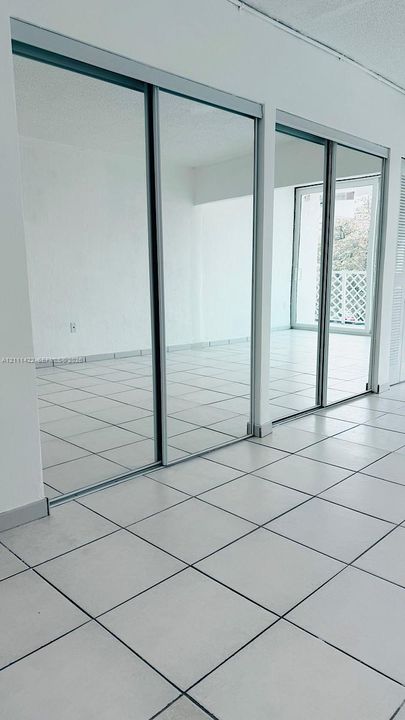 Floor-to-ceiling mirror-paneled sliding closet doors with metallic trim and neutral ceramic tile flooring