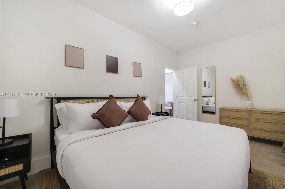 Neutral interior space featuring wood-finish flooring, a six-panel interior door, and a flush-mount ceiling light fixture