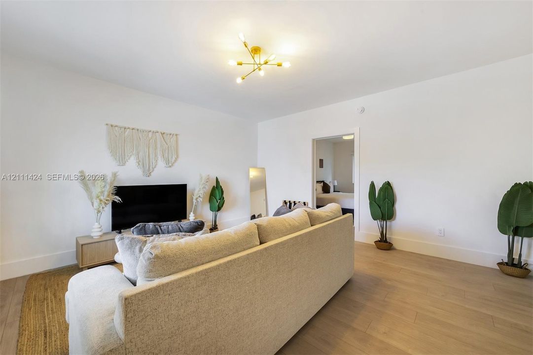 Spacious interior featuring wood-finish flooring, neutral wall paint, and a multi-arm brass finish light fixture