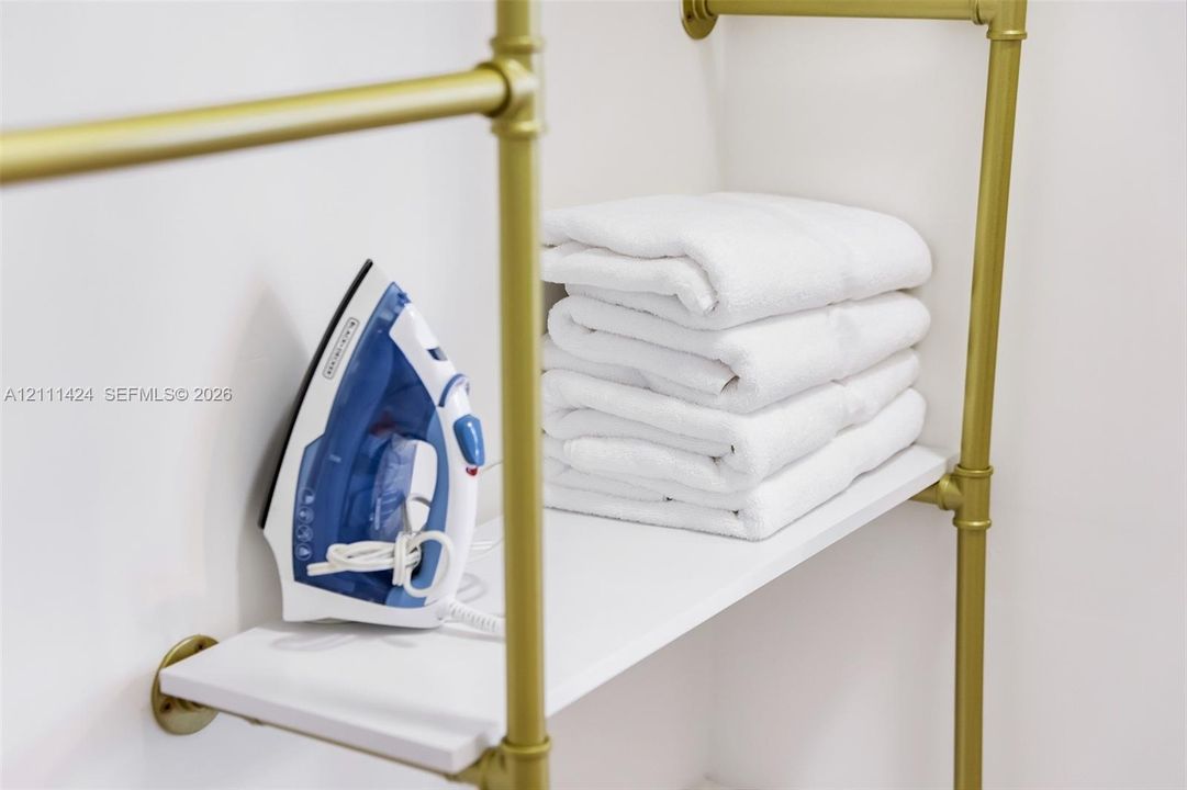 Wall-mounted storage unit featuring gold-tone metallic piping and white shelving