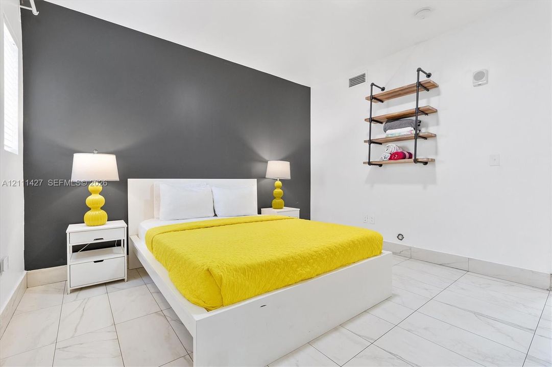 Charcoal accent wall with light-toned floor tiling and industrial-style mounted wooden shelving featuring metal pipe brackets