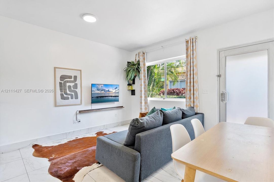 Neutral-toned interior featuring large-format tile flooring, a horizontal wall-mounted floating shelf, a multi-pane sliding window, and a glass-paneled exterior door