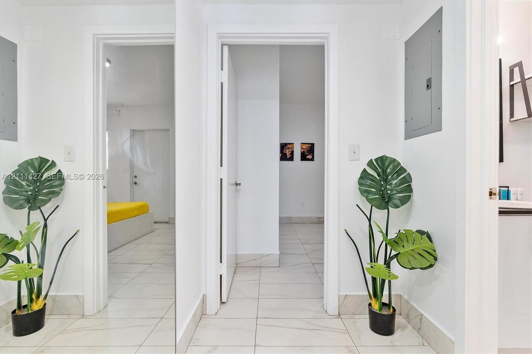Interior hallway featuring large-format light-toned tile flooring, clean white walls, and multiple door casings