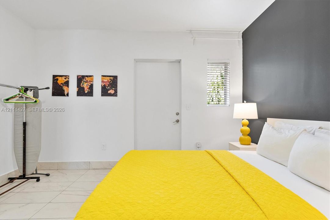 Room featuring light-toned tile flooring, a dark charcoal accent wall, and a single-panel interior door with a silver-finish knob