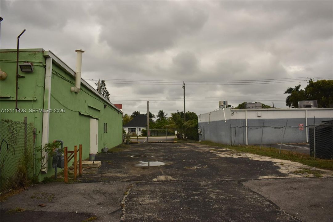 Paved exterior lot featuring metal-sided structures and chain-link fencing