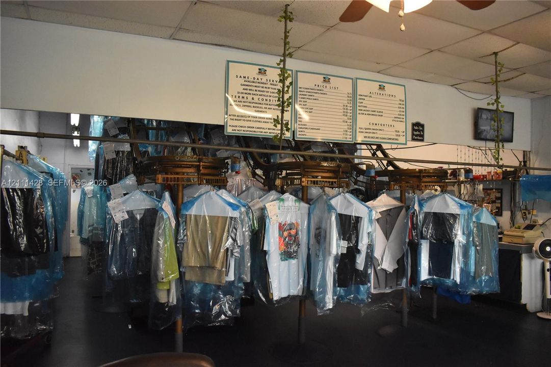 Commercial interior featuring mechanical garment conveyor systems and wall-mounted administrative signage