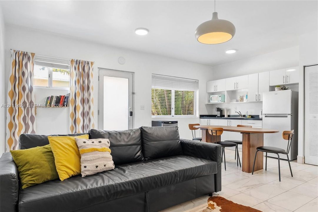Open-concept space featuring tile flooring, white cabinetry, a built-in wall shelf, flush-mount ceiling lighting, and a dome pendant fixture