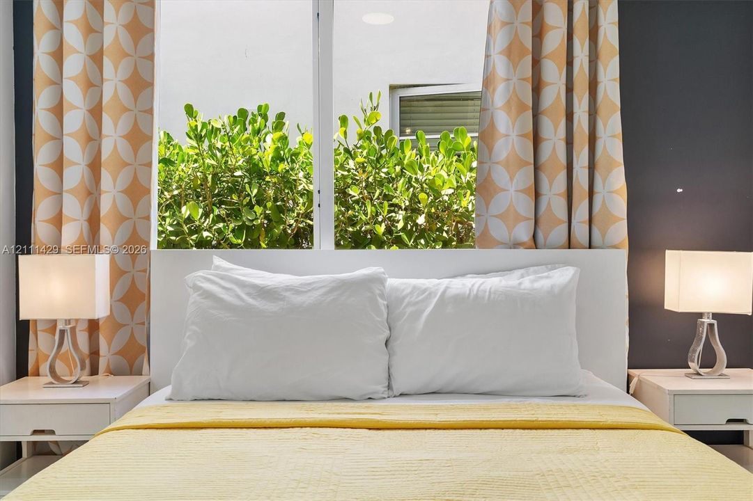 Large window with natural light, white integrated headboard, and dual built-in bedside surfaces