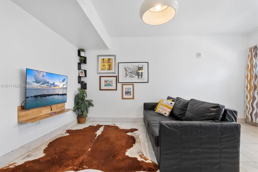 Interior space featuring tile flooring, a wall-mounted wood-finish media shelf, a built-in vertical corner shelving unit, and a dome-style pendant light fixture