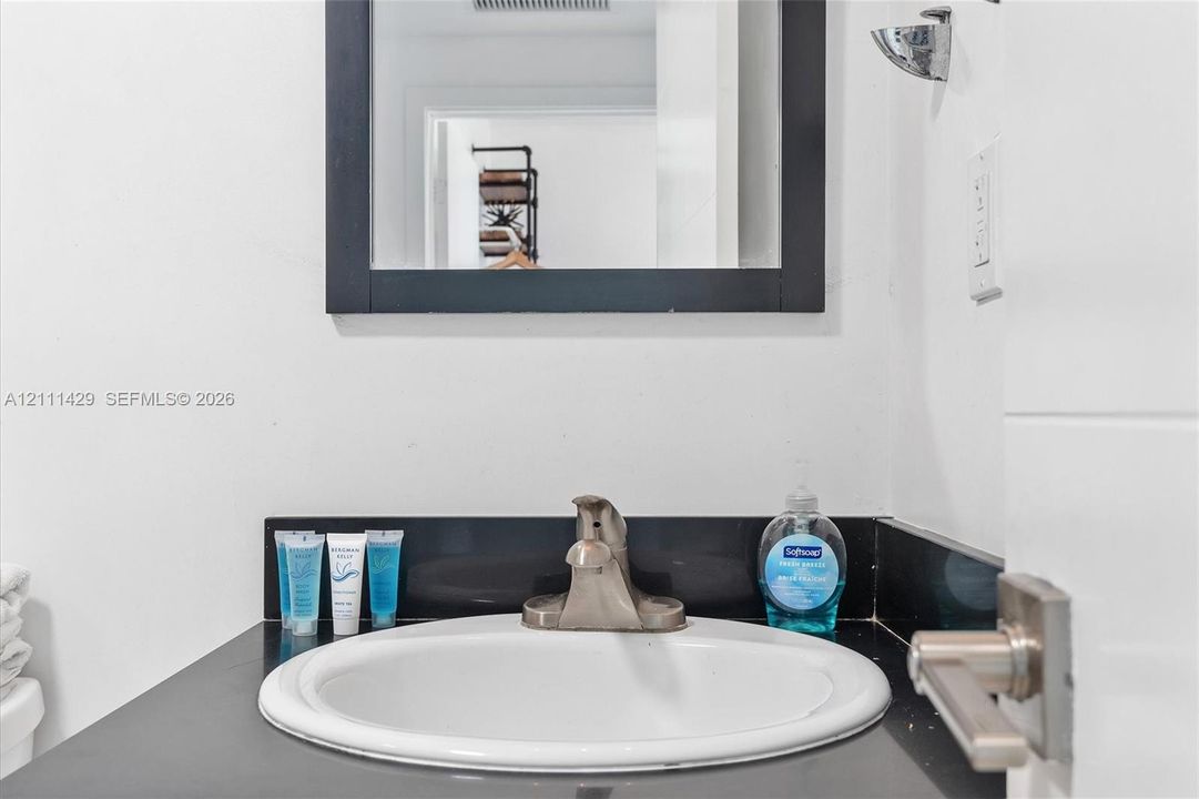 Bathroom vanity featuring a dark countertop, integrated white basin, metallic faucet, and a black-framed wall mirror