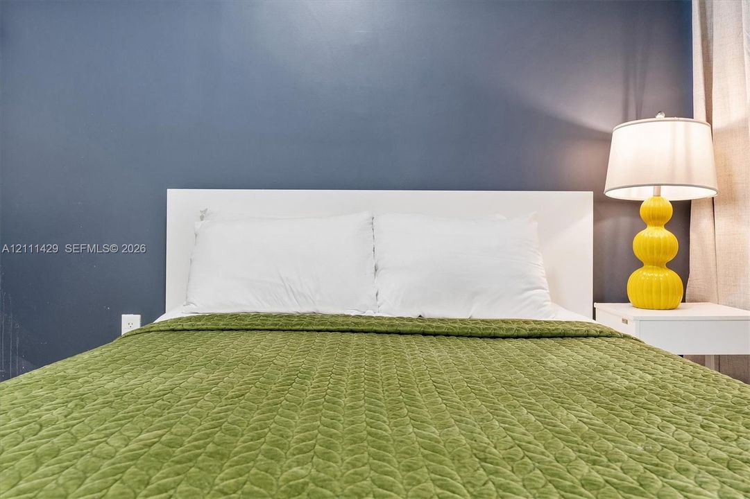 Room featuring a solid-color dark blue accent wall and a built-in white headboard