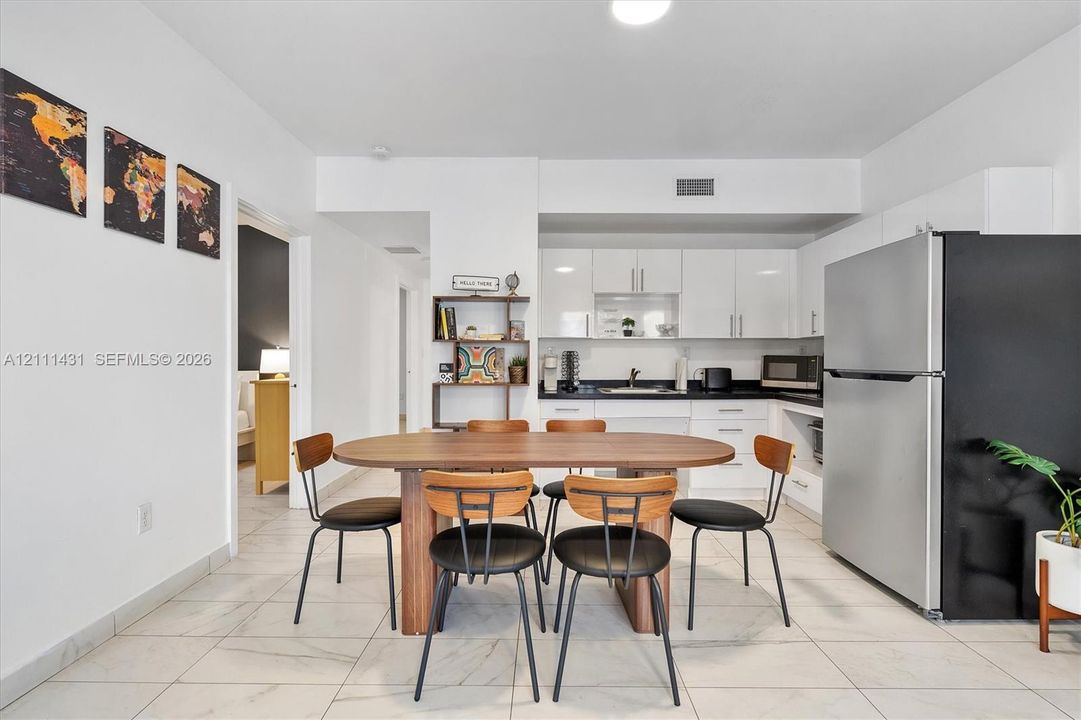 Kitchen featuring white cabinetry, solid-surface countertops, and stainless steel refrigerator, complemented by tile flooring