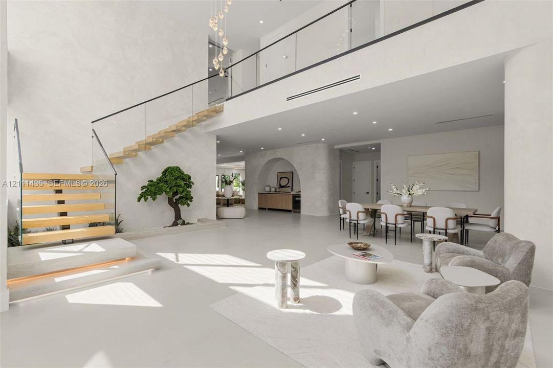 Open-concept interior featuring a floating staircase with wood treads and glass railings, polished concrete flooring, a custom arched wall niche, and recessed ceiling lighting