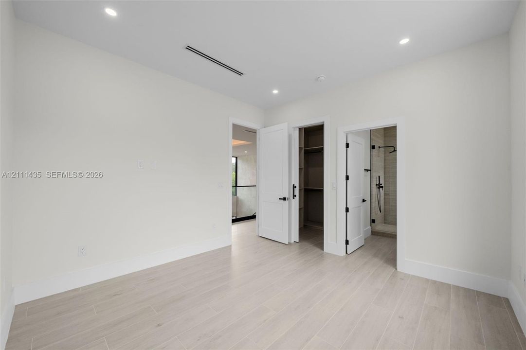 Neutral room with wood-finish flooring, recessed lighting, built-in closet shelving, and shaker-style interior doors