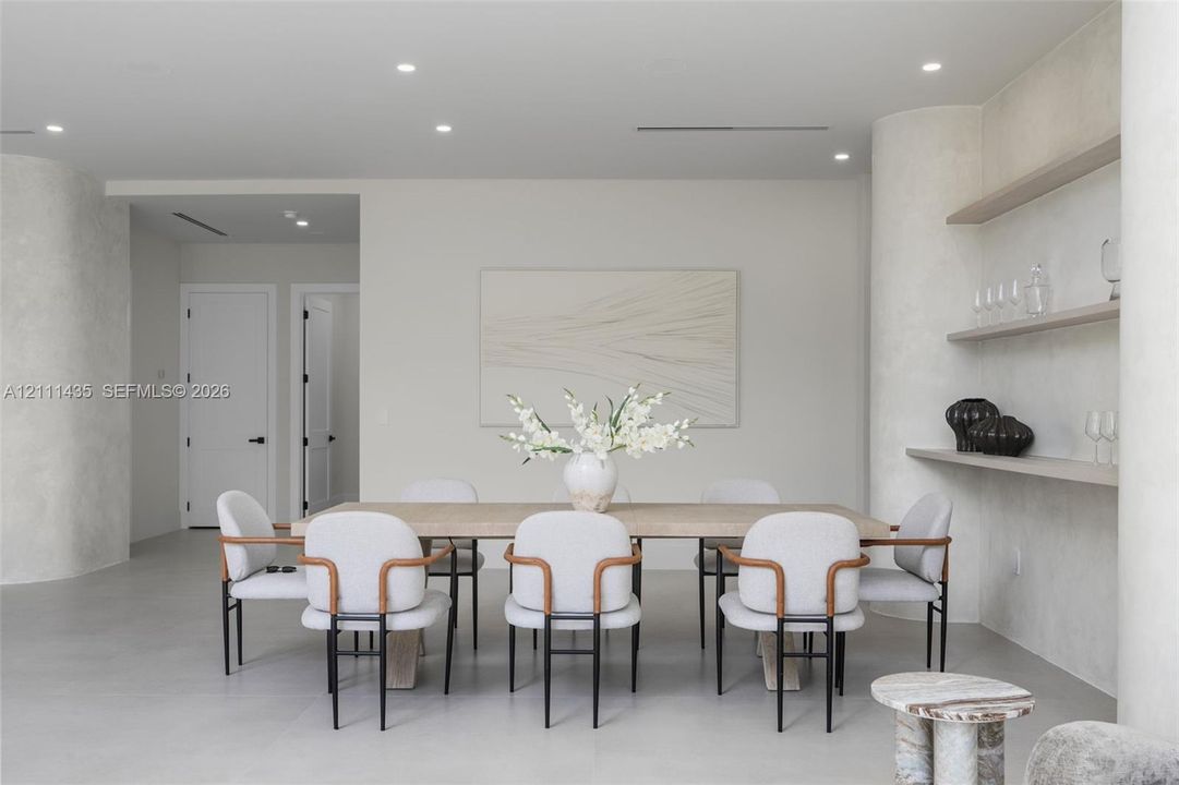 Interior space featuring smooth plaster wall finishes, curved structural columns, integrated wall shelving, recessed ceiling lighting, and solid-core paneled doors