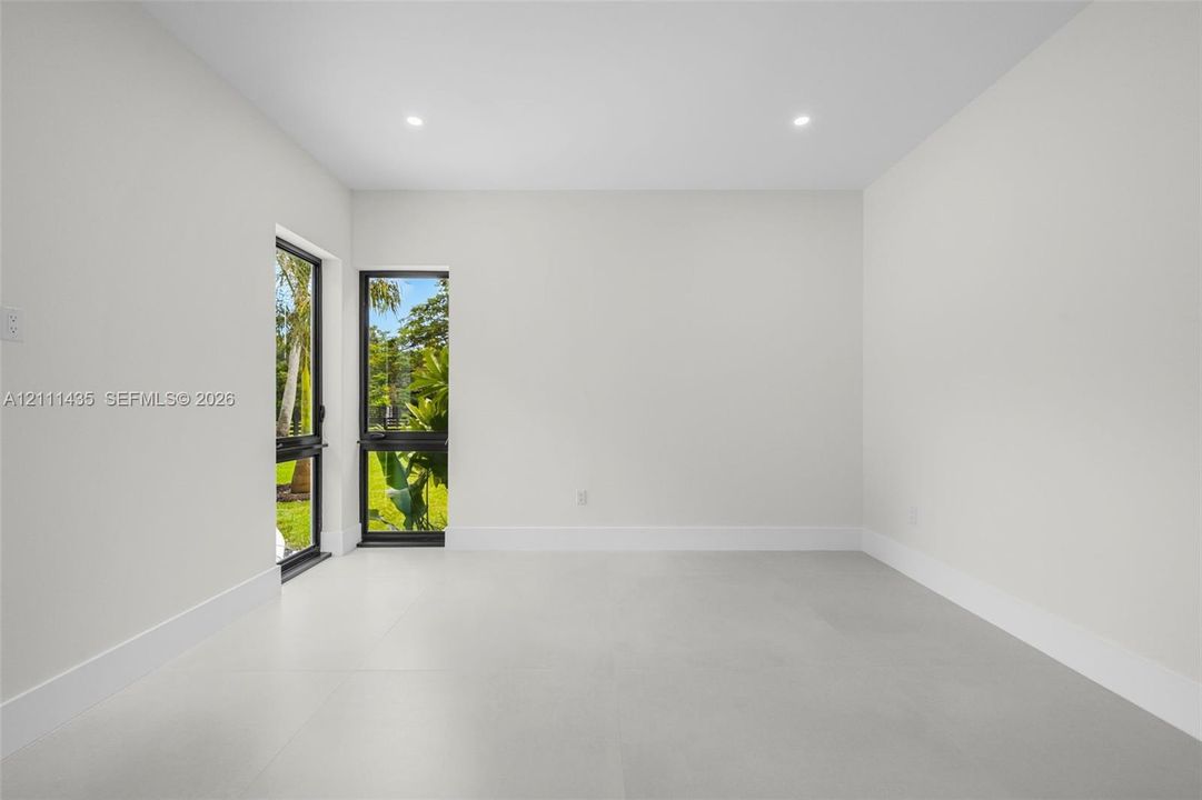 Interior space featuring large-format neutral tile flooring, recessed ceiling lighting, and black-framed glass exterior doors