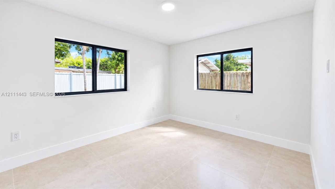 Neutral-toned oversized tile flooring, dual-aspect windows with black frames, and recessed lighting