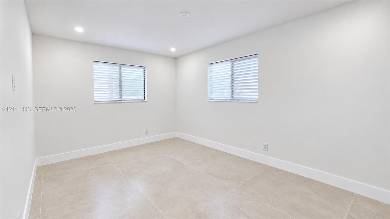 Neutral-toned tile flooring, two horizontal windows featuring integrated blinds, and recessed ceiling lighting