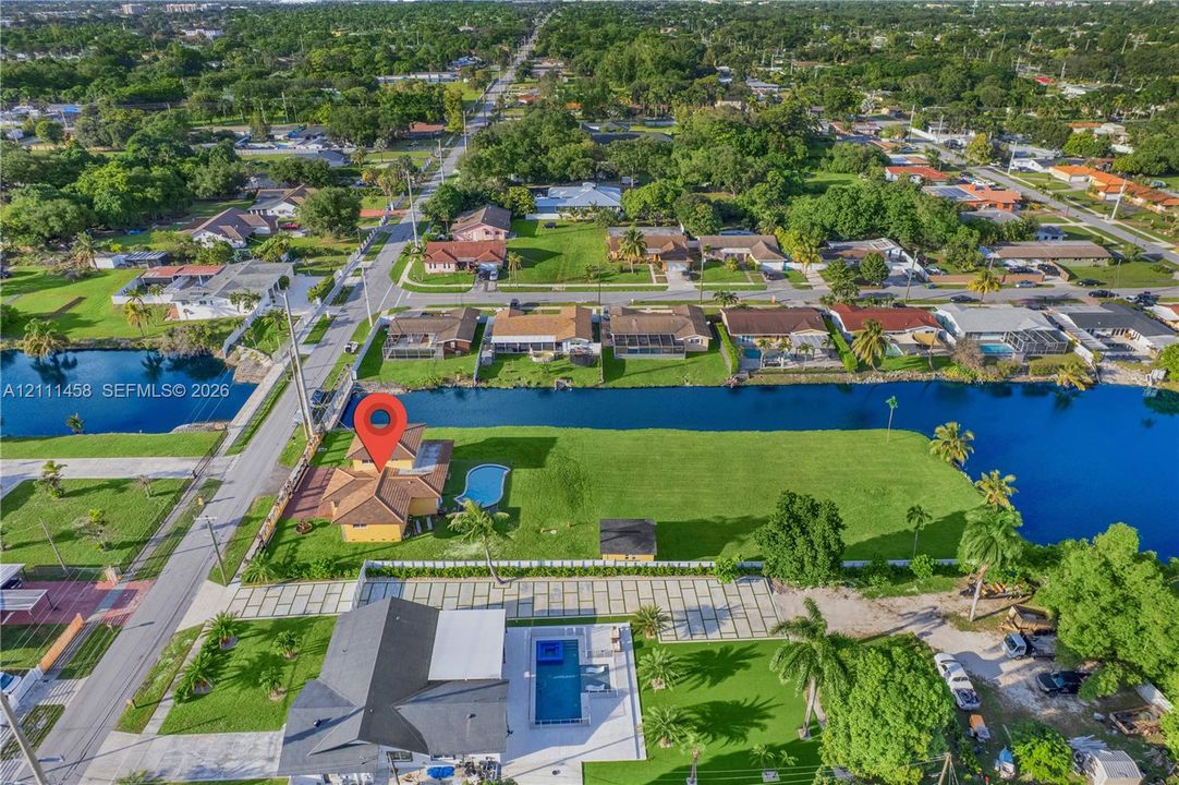 Waterfront lot featuring a private swimming pool, expansive lawn, tile roof, and paved driveway