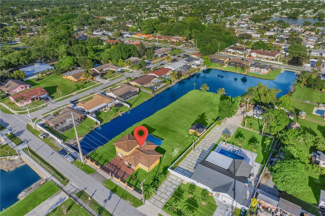 Aerial perspective of a single-family residence featuring a tiled roof, a private swimming pool, and direct canal frontage