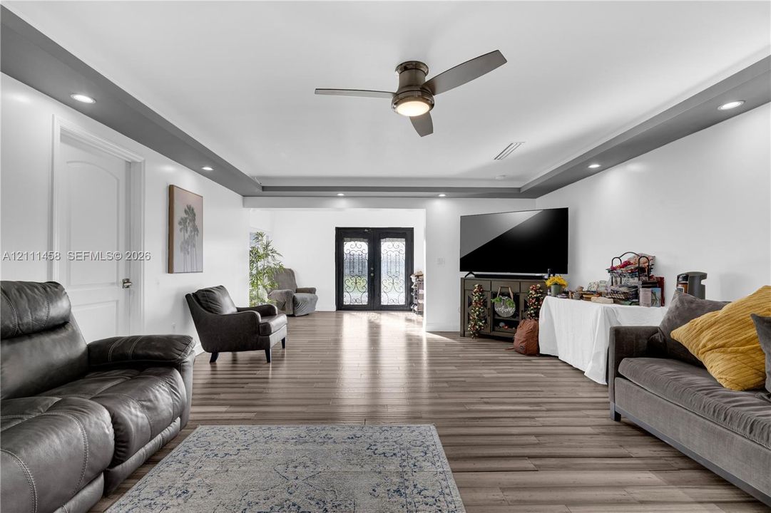 Interior space featuring tray ceiling with recessed lighting, double entry doors with decorative iron detailing, and a central ceiling fan