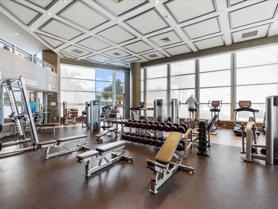 Fitness center featuring a coffered ceiling, floor-to-ceiling windows, and impact-resistant rubber flooring
