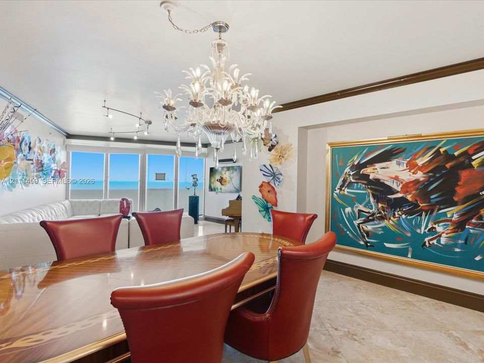 Intricate crystal chandelier, stone flooring, crown molding, and large-format glass panels with ocean scenery