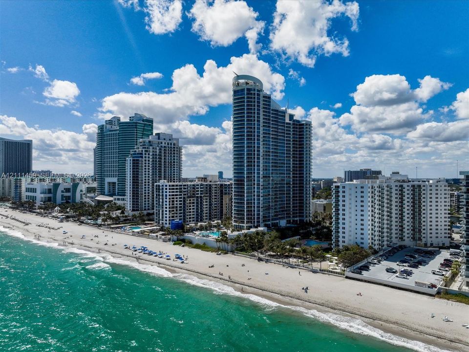 High-rise coastal architecture featuring glass curtain walls and direct access to an expansive sandy beach