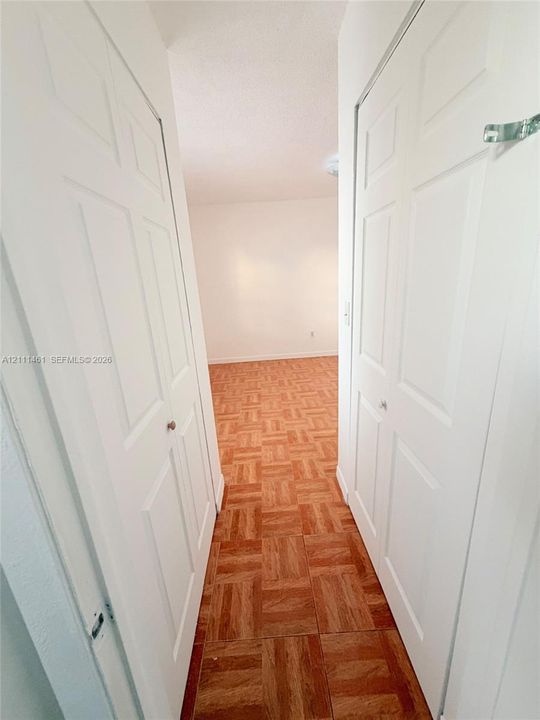 Parquet wood-finish flooring and two sets of white six-panel interior doors with metallic hardware