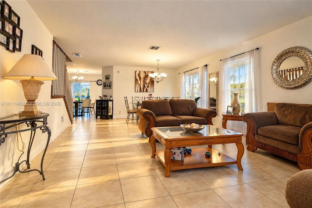 Neutral-toned tile flooring, recessed lighting, multi-arm chandelier, and open-plan layout