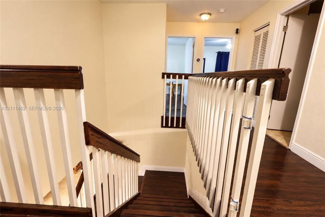 Staircase featuring wood-finish treads and dark wood handrails paired with white vertical balusters