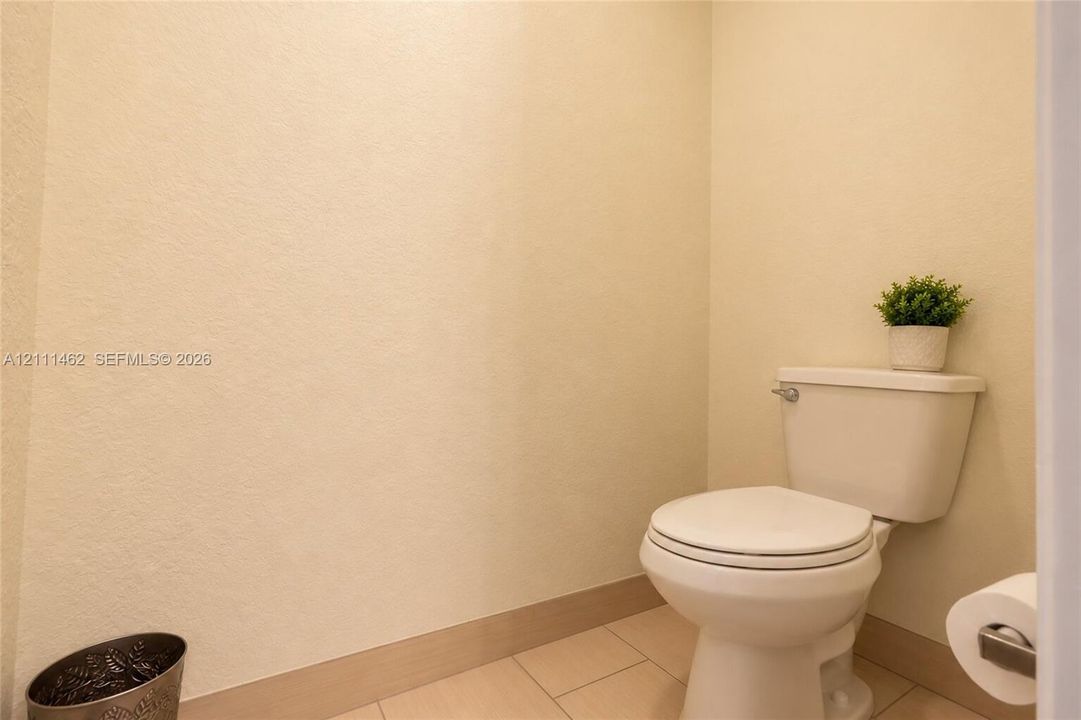 Standard height porcelain toilet with a matching tank and square-tile flooring
